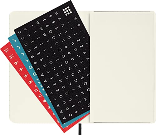 Closed cream-colored Moleskine diary with alphabet stickers, red and teal accents.