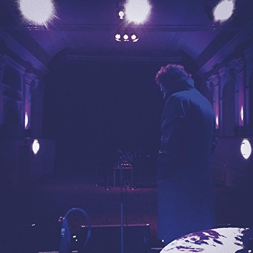 Back view of a person in a coat on a dimly lit stage.