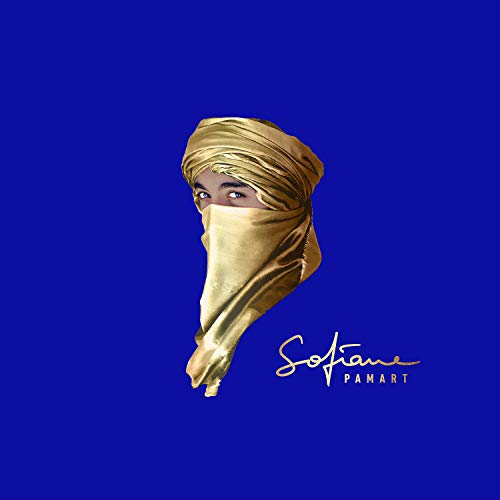 A person wearing a gold headwrap and face covering against a solid blue background.
