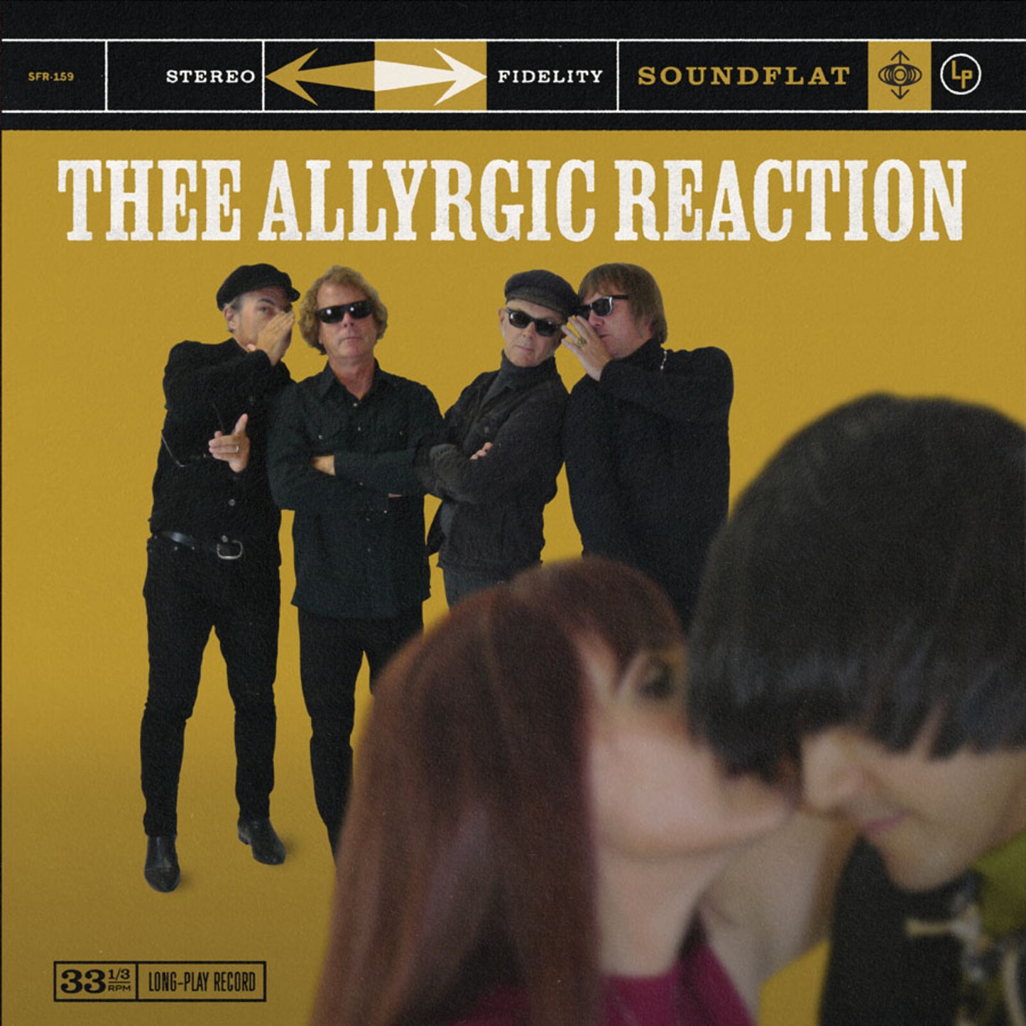 Vinyl record cover featuring a band in dark suits and a blurred foreground.
