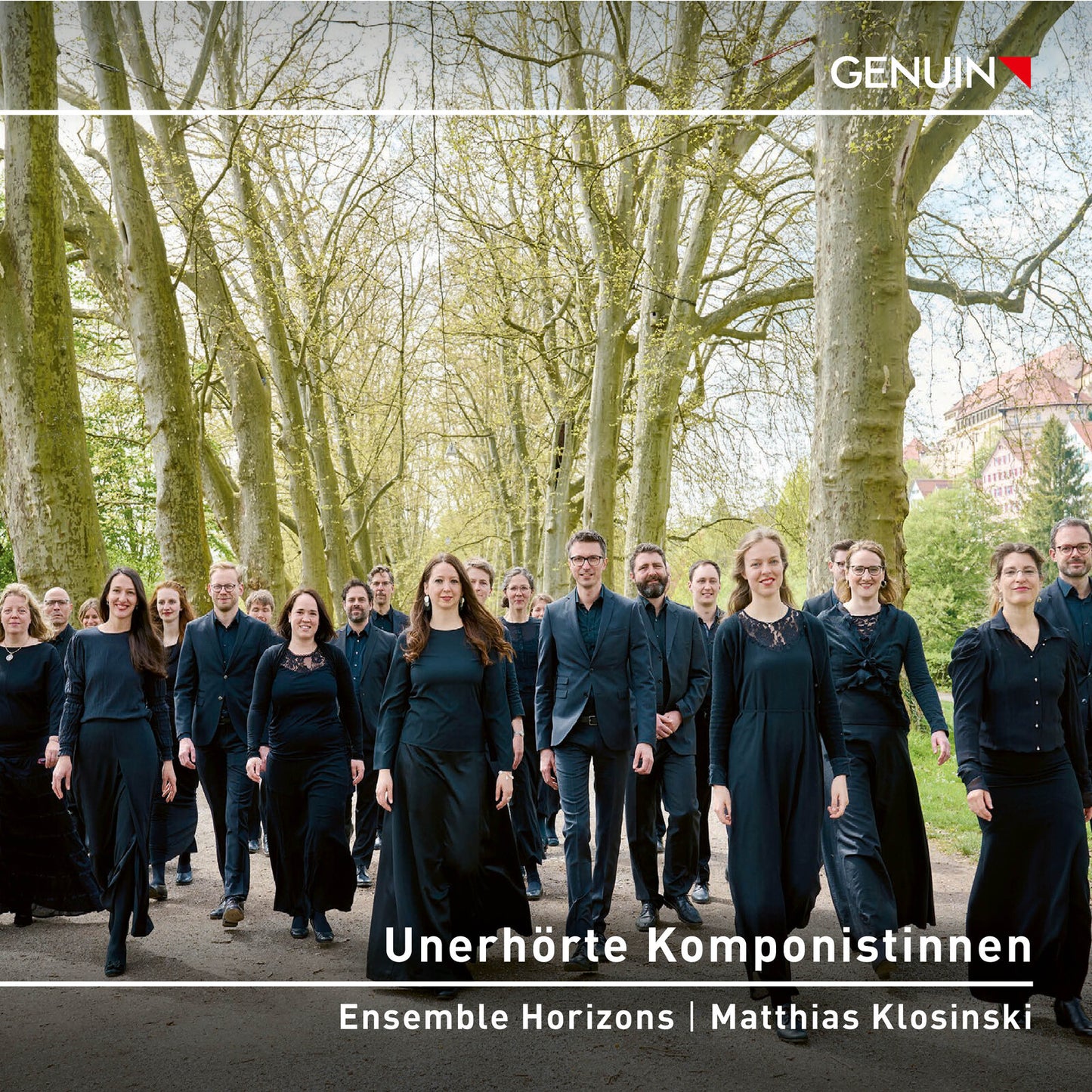 A group of musicians in black attire walking along a tree-lined path.