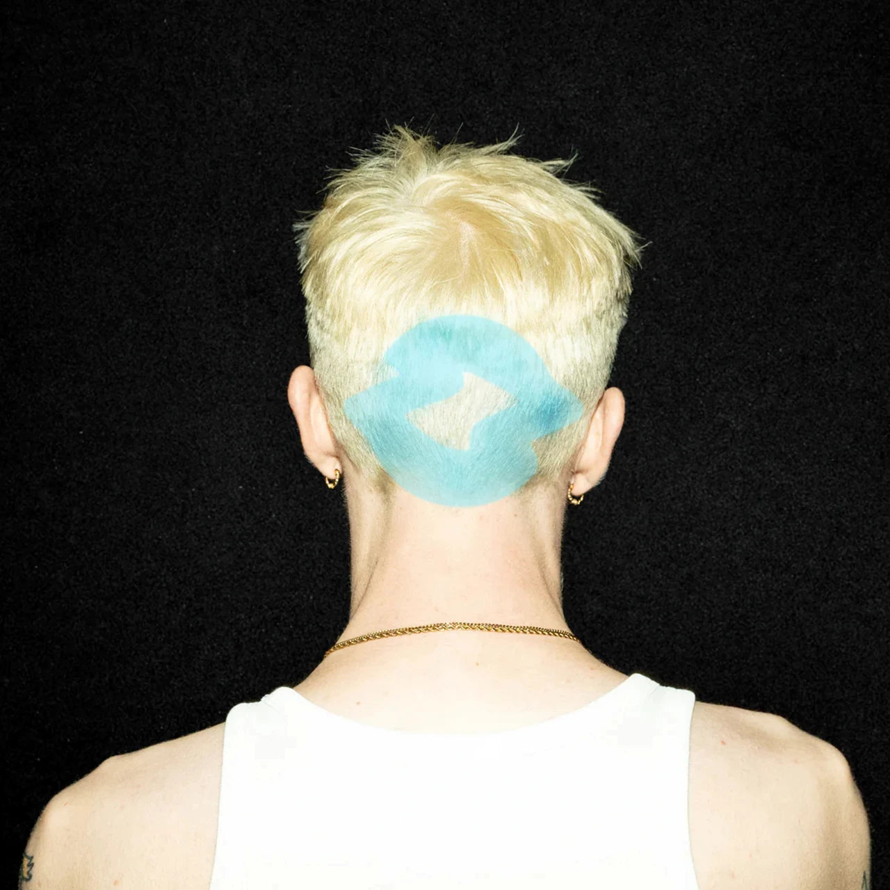 Person with short blonde hair and a blue shape on the back of head.