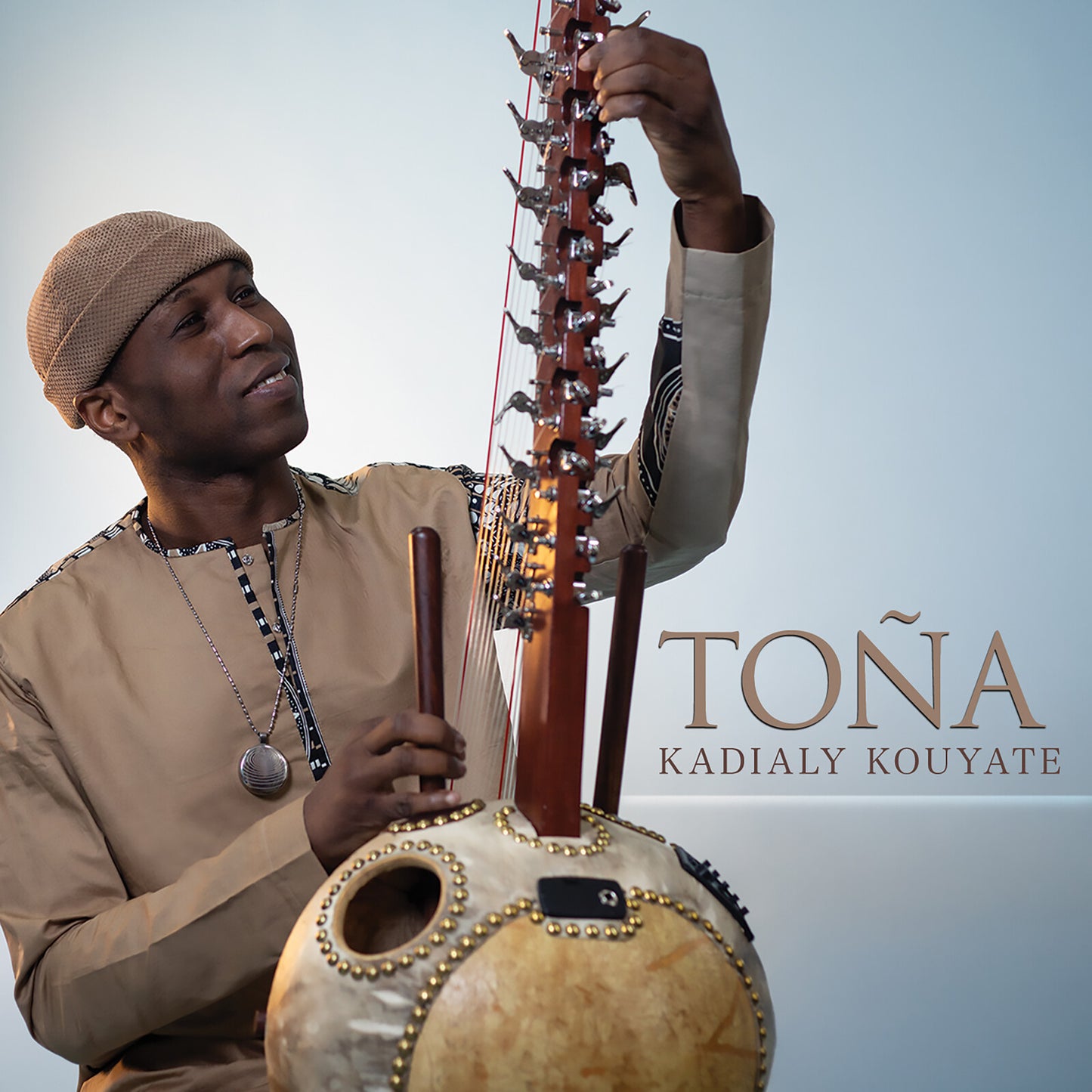 Man playing a large, stringed kora instrument, album cover art.