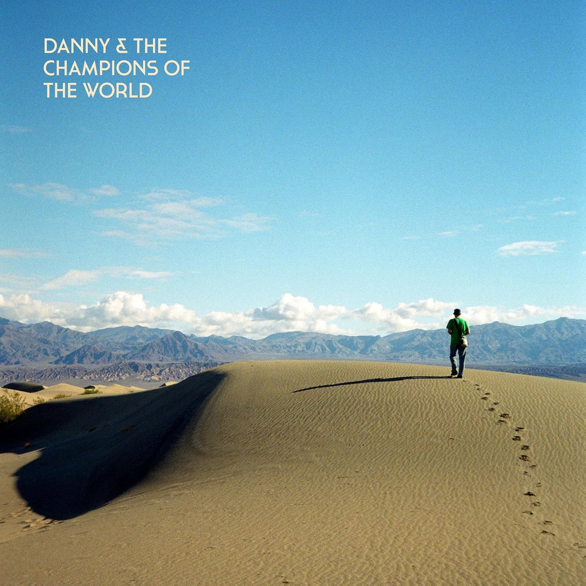 CD cover: desert landscape with a lone figure walking on dunes.
