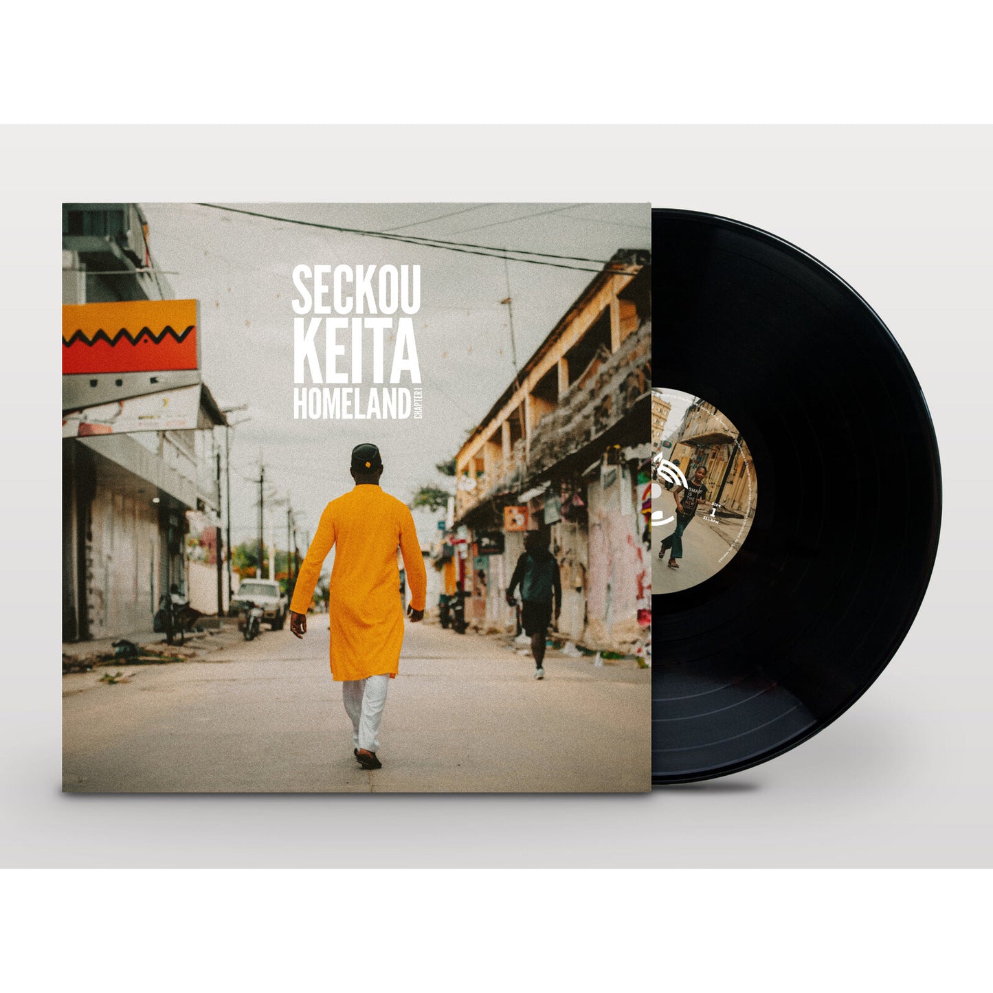 Vinyl record and album cover showing a man in a yellow tunic walking down street.