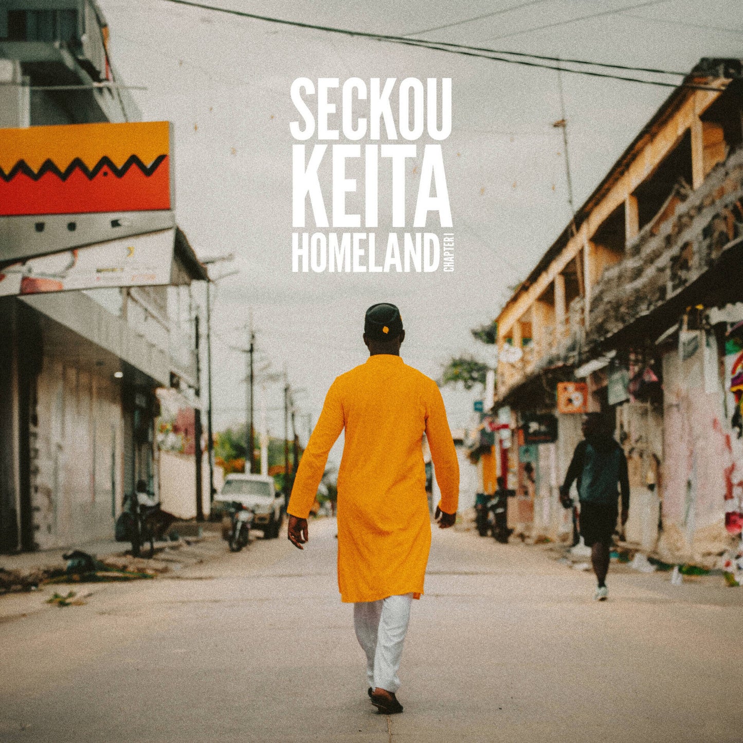 CD cover: man in orange walking down a street in Senegal.