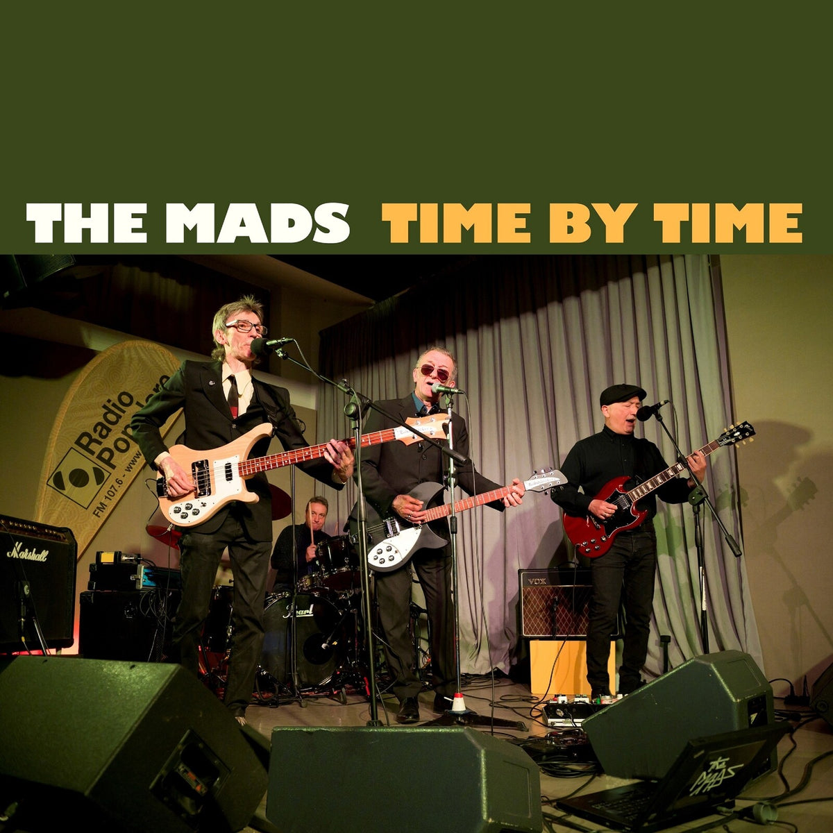 Four musicians performing on stage with instruments and amplifiers.