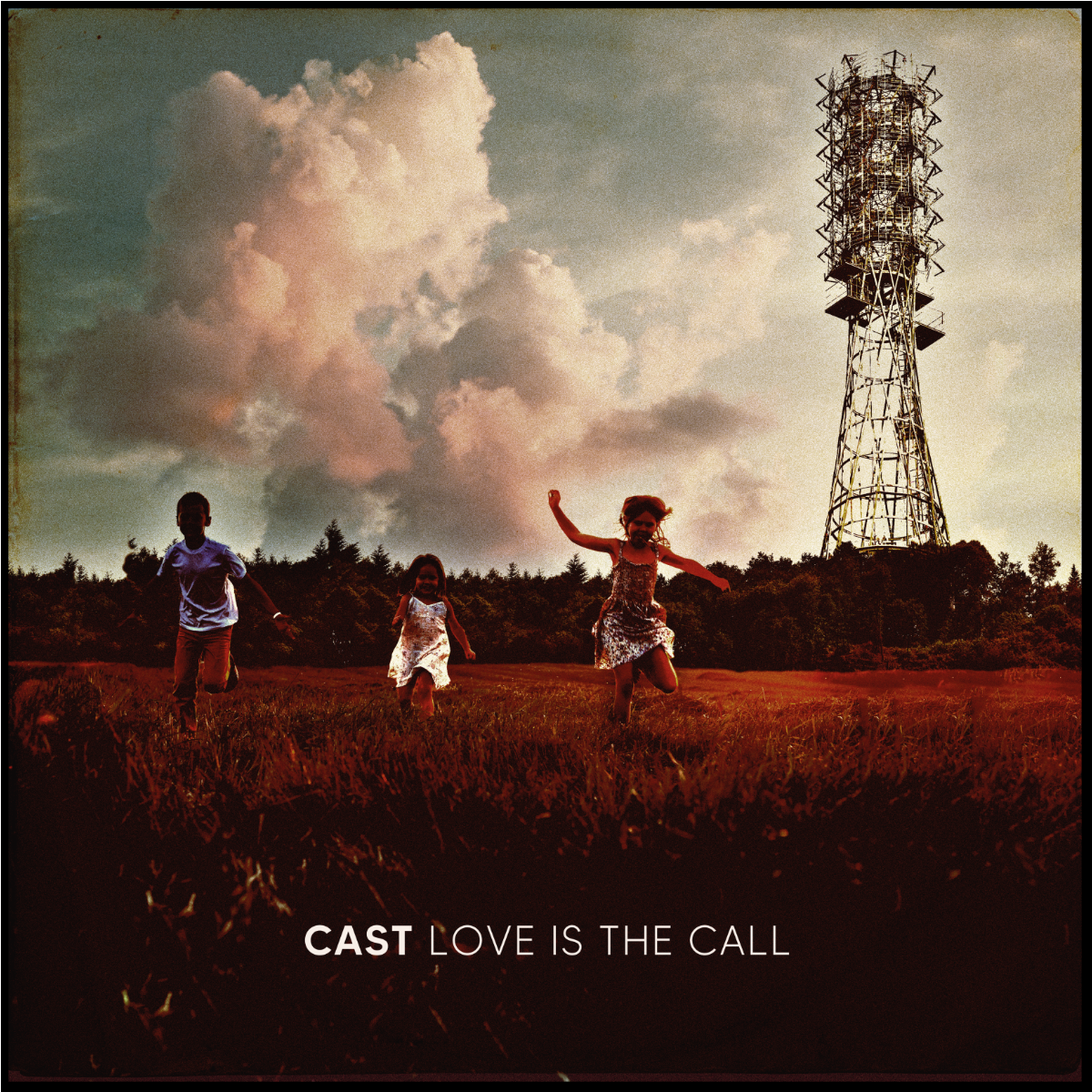 Three children run through a field toward a tall telecommunications tower under cloudy skies.