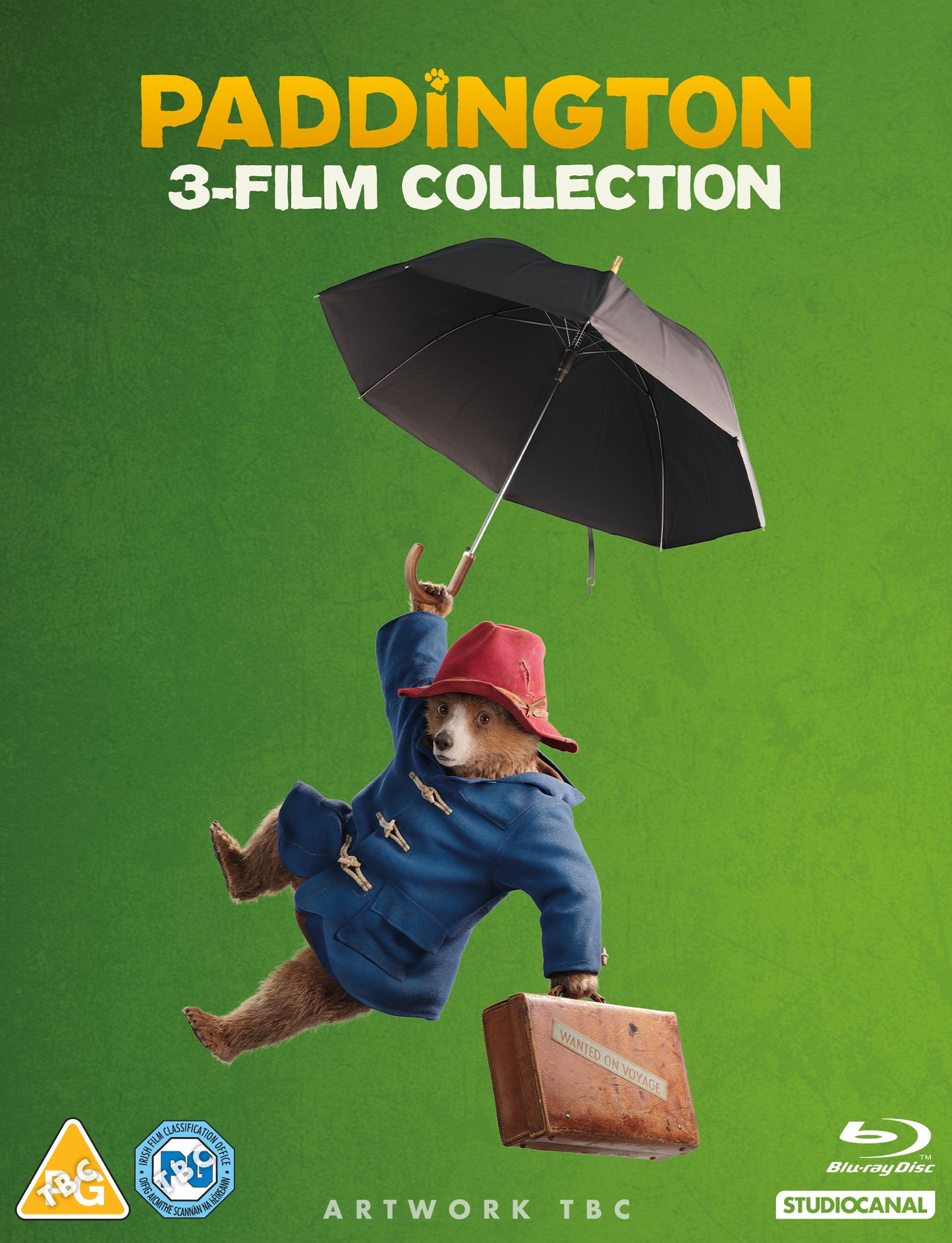 Paddington Bear floats with a suitcase under an open umbrella.