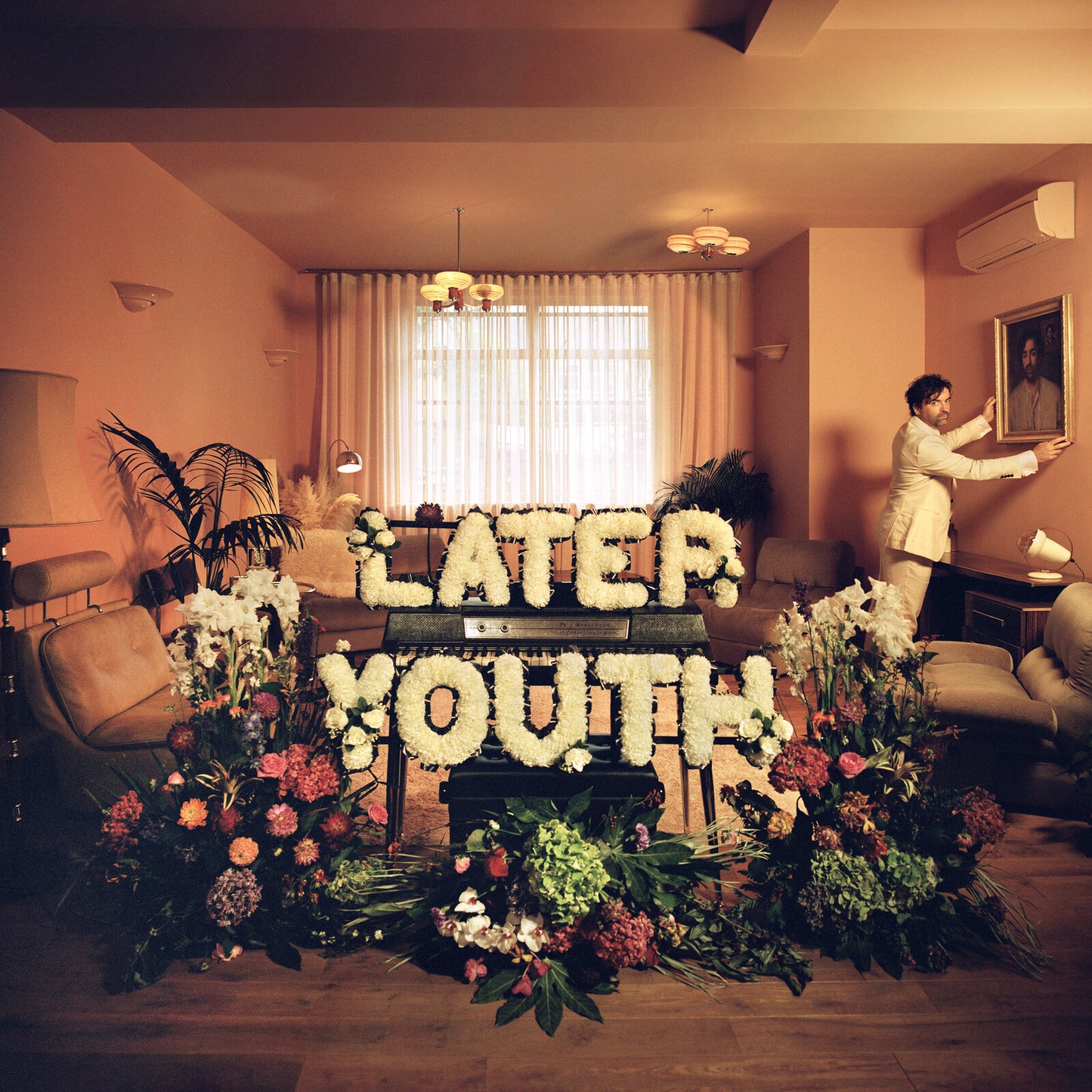 Album cover with a floral-covered coffin and a man in a suit.