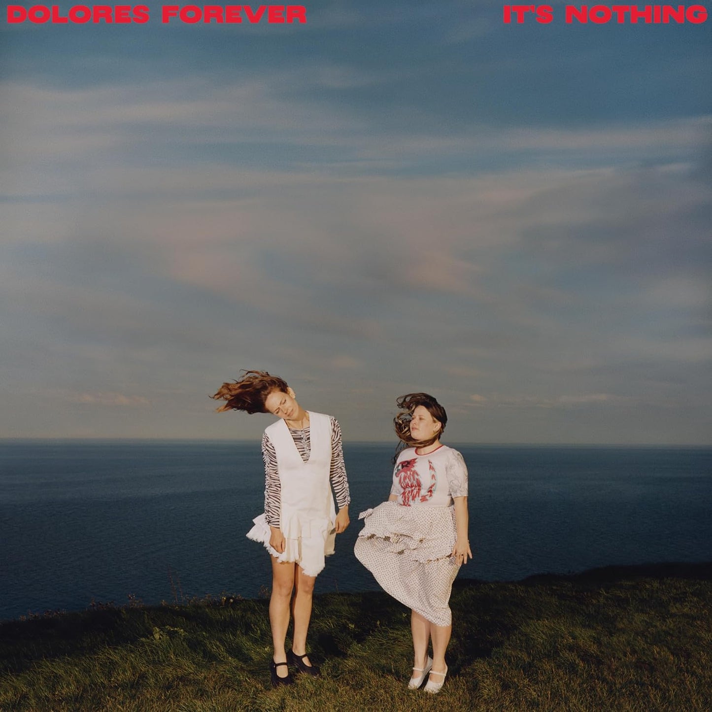 CD cover featuring two women in dresses standing in a grassy field by the sea.