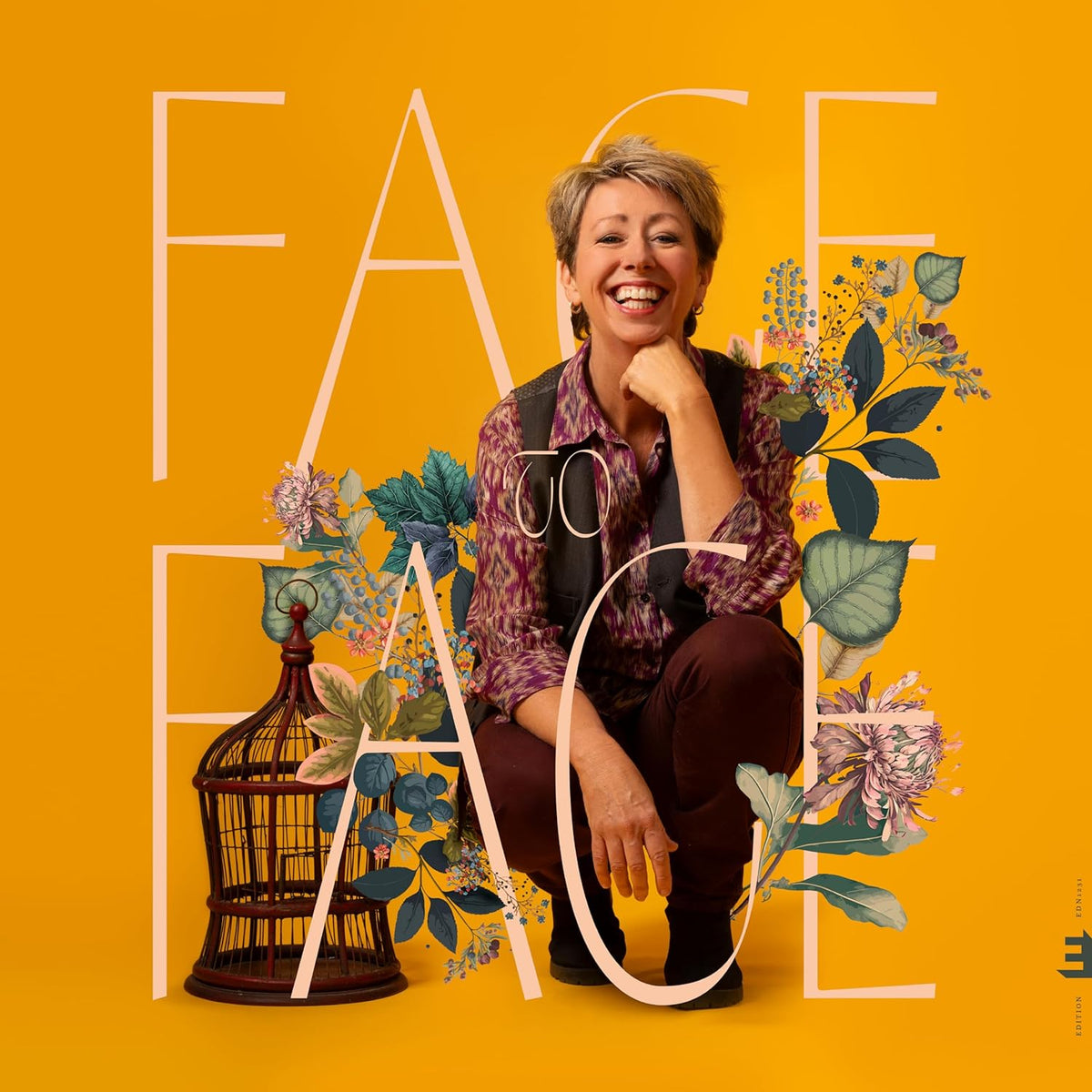 Woman smiling beside large text and floral arrangements on yellow background.