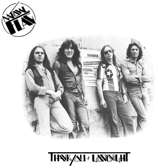 Black and white photo of a four-man rock band posing against a wall.