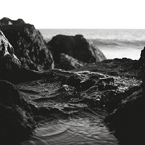 Black and white photo of rocky coastline with ocean waves.