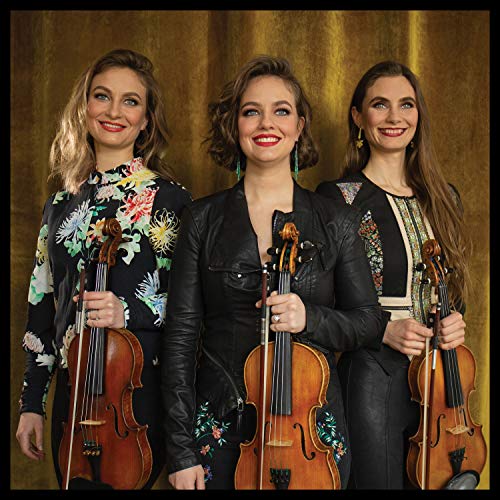 Three women holding violins, posing against a gold curtain backdrop.