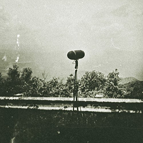 Grainy black and white image of a radio antenna against trees.