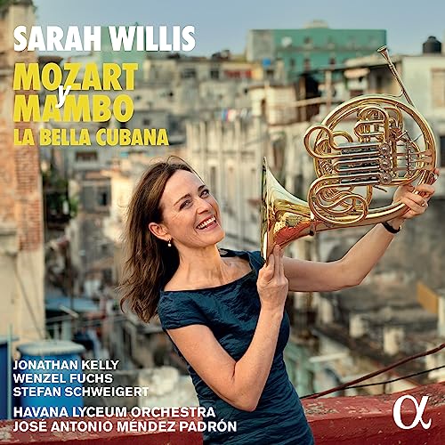 Woman holding a golden French horn with a city backdrop.