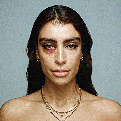 Close-up portrait of Sevdaliza with a bruised eye and layered necklaces.
