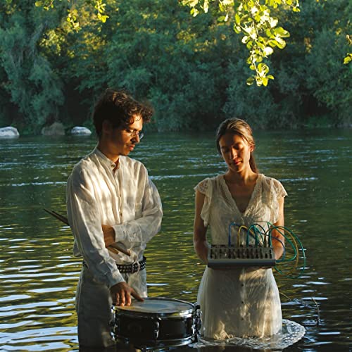 Two people with musical instruments stand in shallow water.