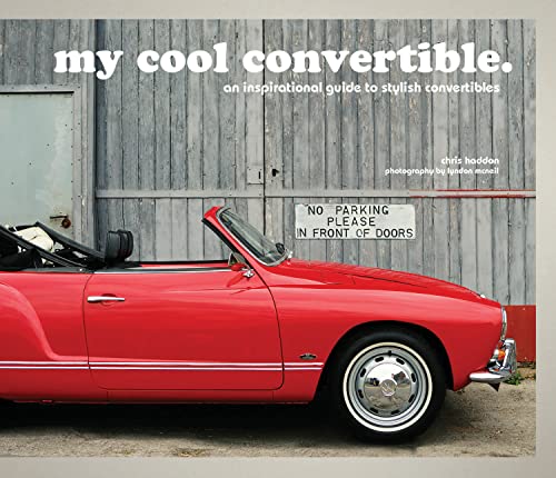 Red vintage convertible car parked in front of a wooden wall.