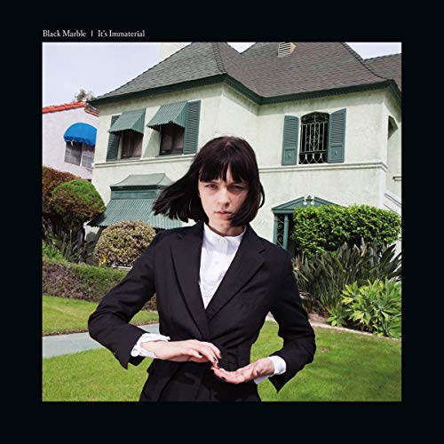CD cover: Woman in suit stands before a light green house.