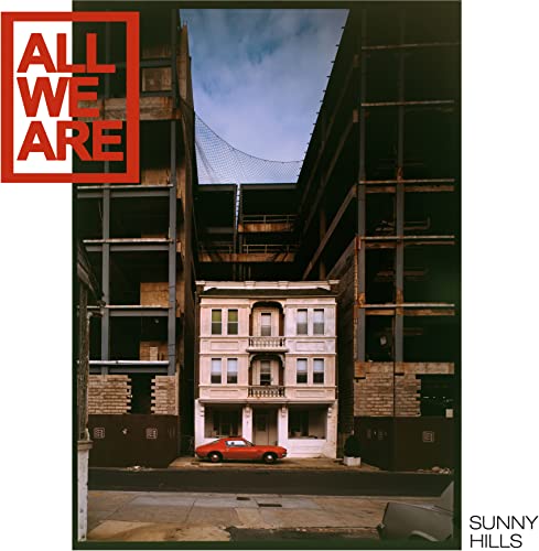 Record cover: a small house between large, unfinished buildings and a red car.