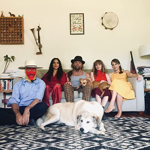 Group portrait of five people and three dogs on a patterned rug.