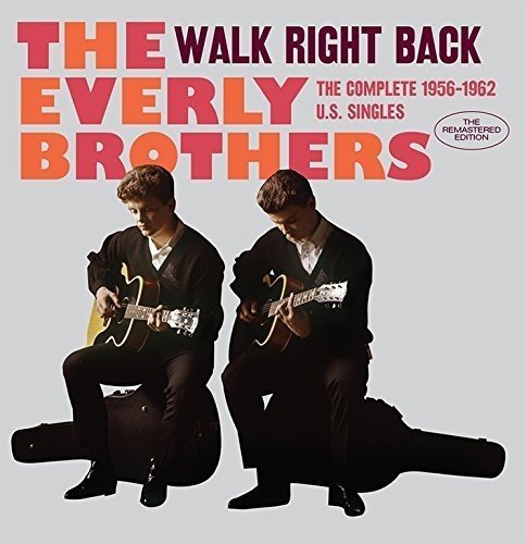 The Everly Brothers sitting and playing acoustic guitars on a grey background.