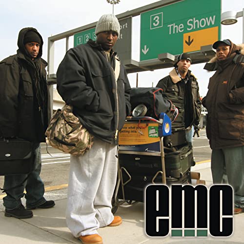 Four men with luggage stand at an airport, album title "emc" overlaid.