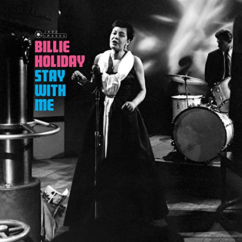 Billie Holiday singing into a microphone on a stage, black and white.