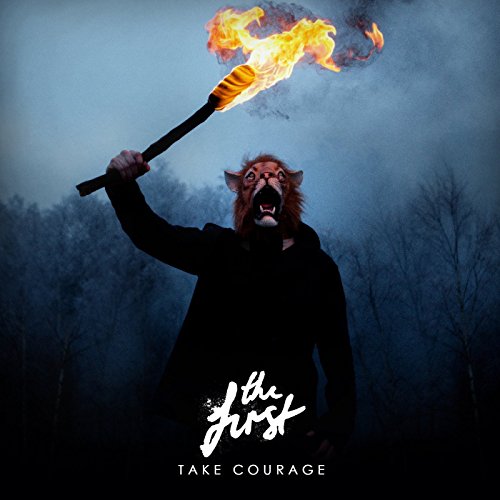 Person in animal mask holds a flaming torch in a forest.
