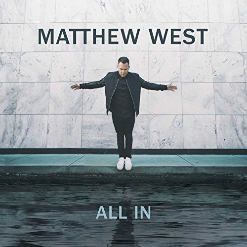 Matthew West stands with arms outstretched over water against a tiled wall background.