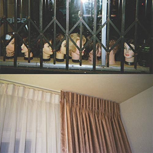 Mannequin heads displayed behind security bars, with a curtain below.