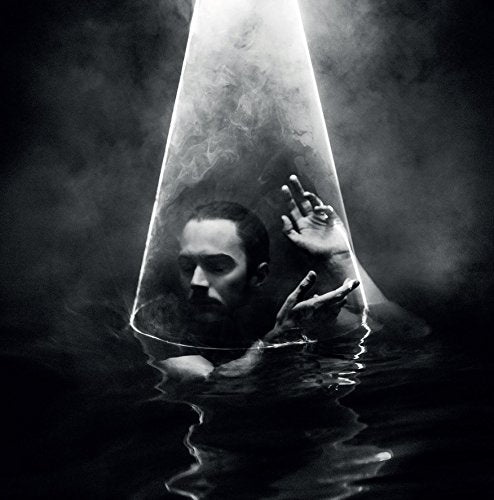 Black and white image of a man submerged with a light cone above.