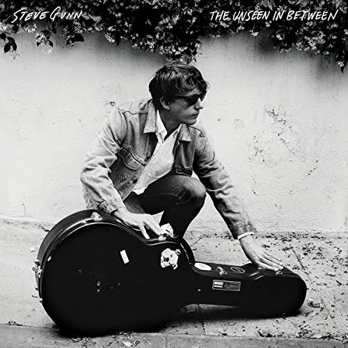Black and white album cover featuring a crouching man with a guitar case.