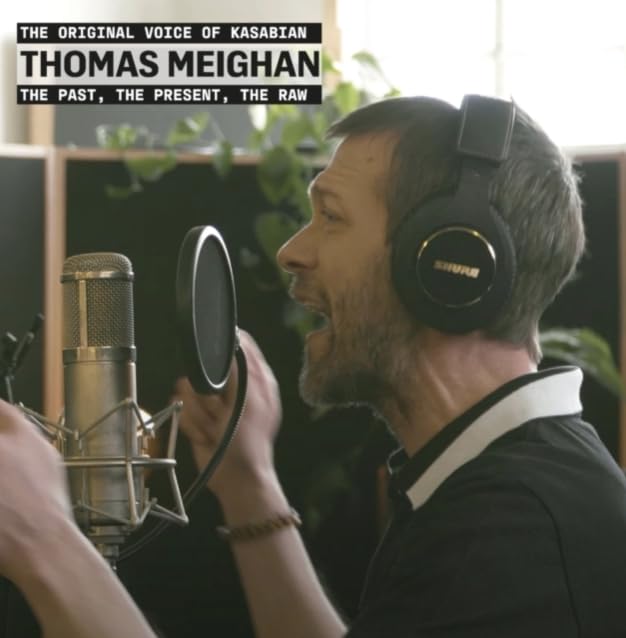Thomas Meighan with headphones and microphone in a recording studio.