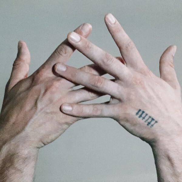 Two pairs of hands with intertwined fingers and a small tattoo.