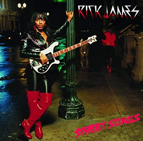 Rick James in leather and red boots holding a bass guitar.
