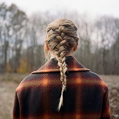 Person with a braided hairstyle wearing a plaid coat, viewed from behind in nature.