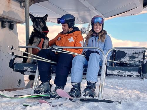 Couple and dog on a ski lift, snowy mountains in background.