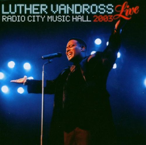 Luther Vandross singing into a microphone on stage, blue background.
