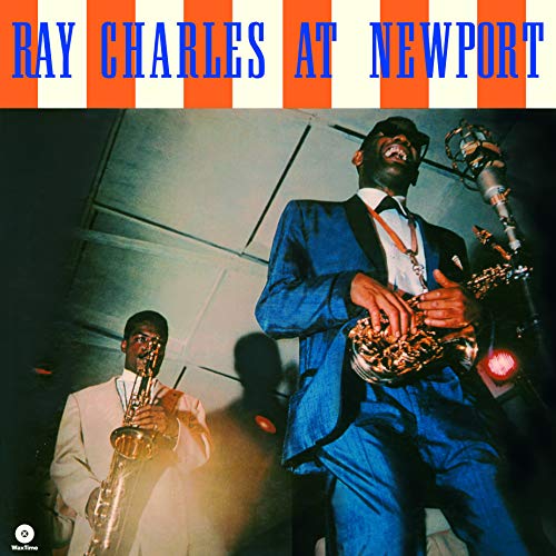 Ray Charles singing into a microphone with a saxophonist on stage.