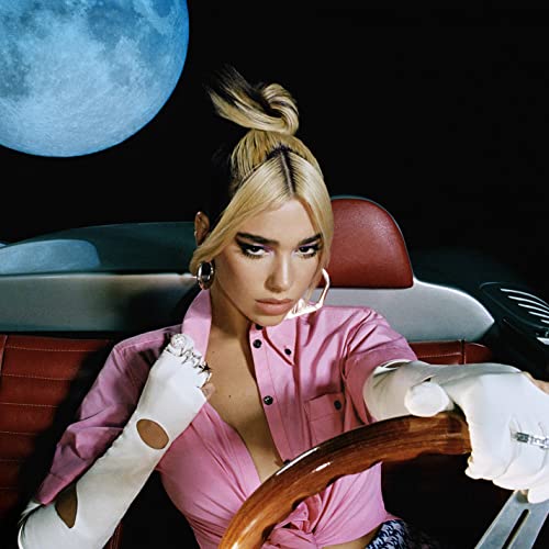 Dua Lipa with blonde hair, pink shirt, and a classic car.