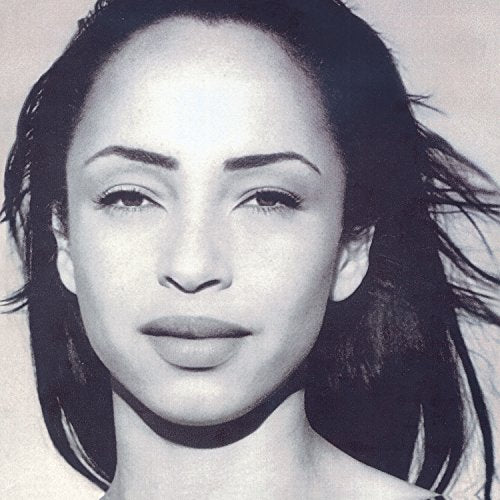 Black and white close-up portrait of Sade with dark hair against a light background.
