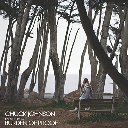 Album cover: lone figure on a bench amidst a grove of windswept trees.