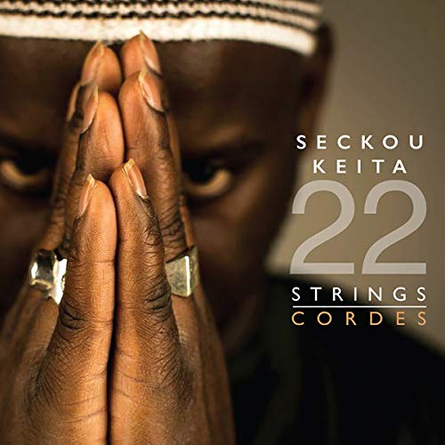 Close-up of Seckou Keita with hands pressed together, album title "22 Strings".