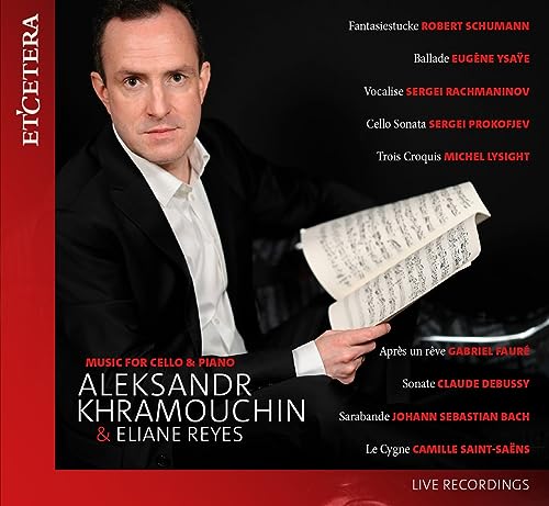 CD cover featuring a man in a suit holding sheet music against black background.
