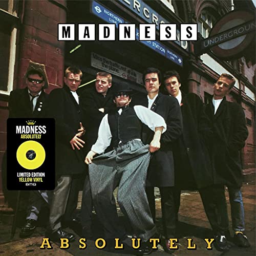 Madness band members in suits pose near a London Underground entrance.
