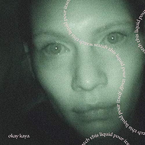 Close-up of a person’s face with text circling, muted green tones.