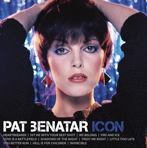 Pat Benatar with short dark hair and blue eyeshadow against a blue bokeh background.